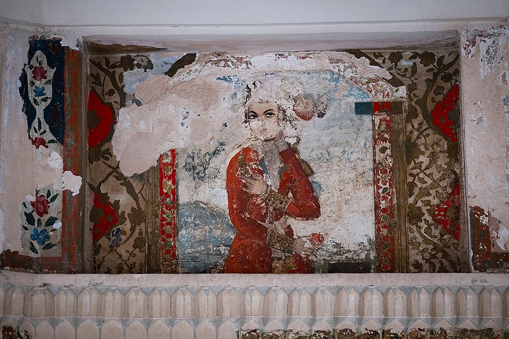 A view of a damaged painting of a woman is on the wall of a historic site in Isfahan, Iran.
