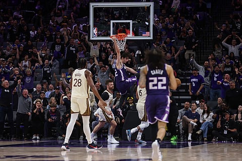 Sacramento Kings center Maxime Raynaud (42) hangs on the rim after dunking the ball during the second half of an NBA basketball game against the Golden State Warriors in Sacramento, Calif.