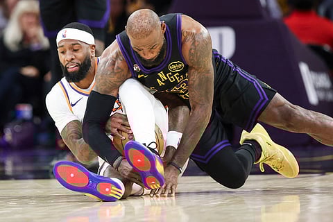 Los Angeles Lakers forward LeBron James, right, and Phoenix Suns forward Royce O'Neale, left, battle for the ball during the second half of an NBA basketball game  in Los Angeles.