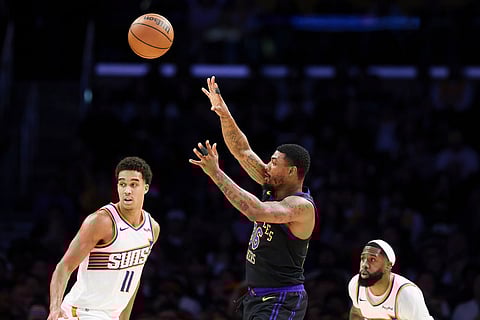 Los Angeles Lakers guard Marcus Smart, center, passes the ball against Phoenix Suns forward Oso Ighodaro (11) as Suns forward Royce O'Neale, right, watches during the first half of an NBA basketball game in Los Angeles.
