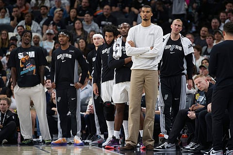 San Antonio Spurs center Victor Wembanyama, second from right, watches play from the bench during the second half of an NBA basketball game against the Denver Nuggets in San Antonio.