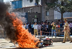 | Photo: PTI : Flames billow as a police bike is set ablaze by factory workers during a protest demanding a hike in wages, in Noida, Gautam Buddh Nagar district, Uttar Pradesh. The protest carried incidents of arson, vandalism and stone-pelting reported from Phase-2 and Sector 60 areas, police said.