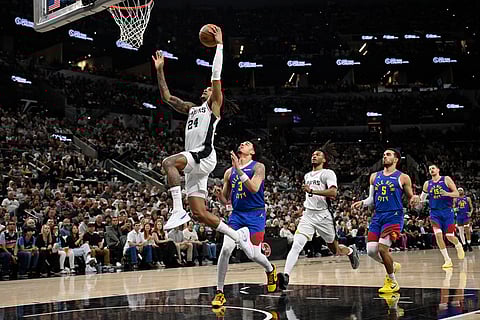 San Antonio Spurs guard Devin Vassell (24) goes to the basket against Denver Nuggets guard Julian Strawther (3) during the first half of an NBA basketball game in San Antonio.
