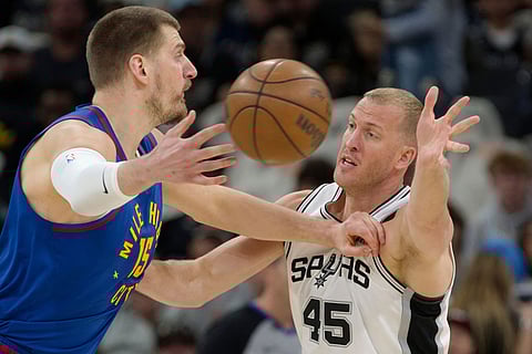 Denver Nuggets center Nikola Jokic (15) passes as he is guarded by San Antonio Spurs center Mason Plumlee during the first half of an NBA basketball game  in San Antonio.