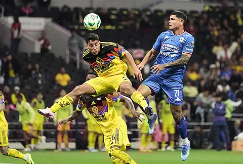 America's Sebastian Caceres, left, heads the ball past Cruz Azul's Gabriel Fernandez during a Mexican soccer league match in Mexico City.
