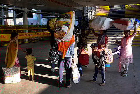 A family balances their entire life on their backs — sacks, bags, and children in tow — as they make their way through the station. 