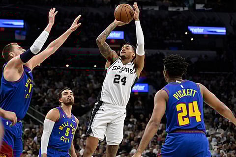 San Antonio Spurs guard Devin Vassell shoots against Denver Nuggets' Nikola Jokic, left, Tyus Jones (5) and Jalen Pickett, right, during the first half of an NBA basketball game in San Antonio.