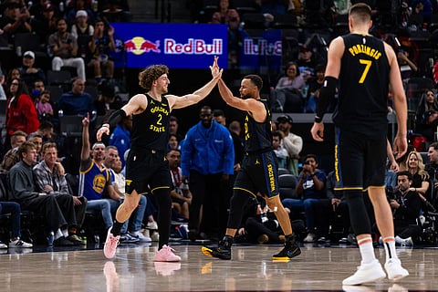 Golden State Warriors guard Brandin Podziemski (2) and Golden State Warriors guard Stephen Curry (30) high five during the first half of an NBA basketball game in Inglewood, Calif.