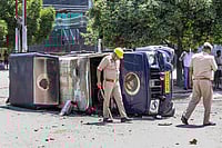 Noida Workers' Wage Protest Turns Violent As Police Clash, Road Blocked | Photo: PTI : Police personnel inspect the wreckage of a vehicle during a protest by factory workers demanding a hike in wages, in Noida, Gautam Buddh Nagar district, Uttar Pradesh. The protest carried incidents of arson, vandalism and stone-pelting reported from Phase-2 and Sector 60 areas, police said.