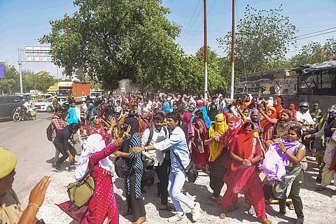 Employees of hosiery units block a road during a protest demanding a salary hike at Phase 2 Hosiery Complex, in Noida.