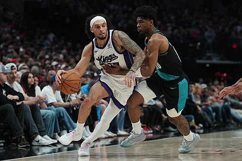 Sacramento Kings guard Devin Carter, left, tries to get past Portland Trail Blazers guard Scoot Henderson (00) during the first half of an NBA basketball game in Portland, Ore.