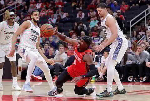Houston Rockets guard Aaron Holiday, center, loses his footing and the ball as he drives to the basket through Memphis Grizzlies guards Jahmai Mashack (21), Rayan Rupert (32) and Lucas Williamson, right, during the second half of an NBA basketball game in Houston.