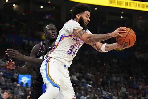 Oklahoma City Thunder guard Kenrich Williams, right, grabs a rebound in front of Phoenix Suns center Khaman Maluach during the second half of an NBA basketball game in Oklahoma City.