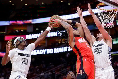 Houston Rockets guard JD Davison (4) attempts to dunk the ball between Memphis Grizzlies guards Jahmai Mashack (21) and Lucas Williamson (55) during the second half of an NBA basketball game in Houston. 