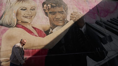 A man walks past a mural by artist Alfredo Segatori depicting late soccer legend Diego Maradona and Italian singer Raffaella Carra dancing tango, in Buenos Aires, Argentina, Monday, April 13, 2026