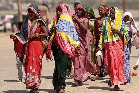 Women walk with their head covered to protect themselves from the sun on a hot summer day, in Prayagraj.