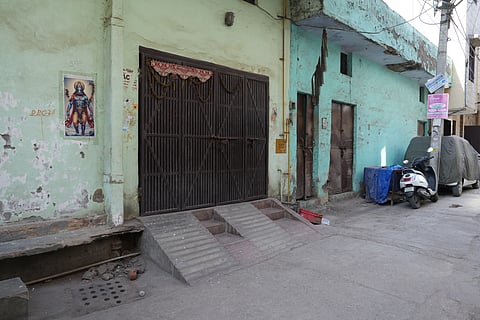 Varaha avatar poster next to the main entrance of a house with a covered cage on the other side in Tri Nagar. 