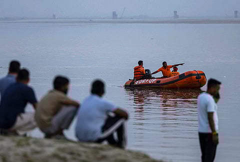 SDRF personnel conduct a search operation on the banks of river Ganga after two persons allegedly drowned while taking a bath, in Prayagraj.