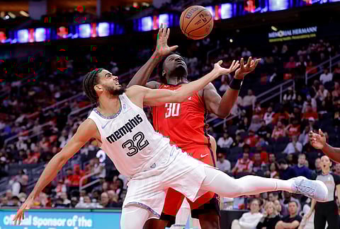 Memphis Grizzlies guard Rayan Rupert (32) and Houston Rockets center Clint Capela (30) bobble a rebound during the second half of an NBA basketball game in Houston.