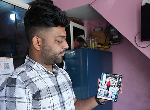 Abdul Bari, 27, showing a photo on his phone of him standing in front of his footwear business in Tri Nagar.