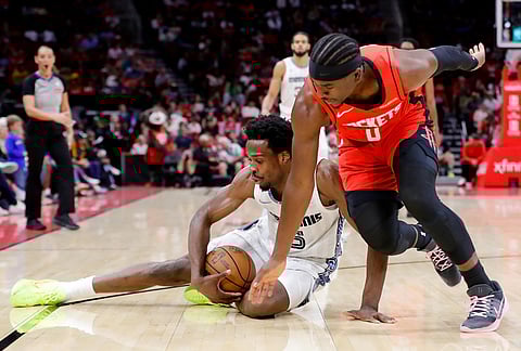 Memphis Grizzlies forward Toby Okani, left, tries to protect the ball after falling from Houston Rockets guard Aaron Holiday, right, during the second half of an NBA basketball game in Houston.
