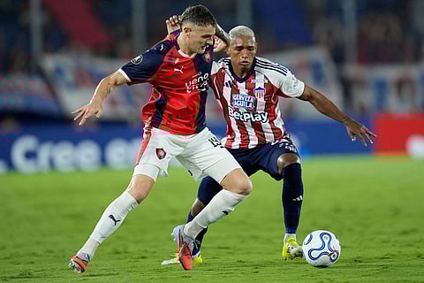 Pablo Vegetti of Paraguay's Cerro Porteño, left, and Jermein Pena of Colombia's Junior struggle for the ball during a Copa Libertadores Group F soccer match in Asuncion, Paraguay.