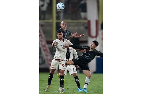 Miguel Silveira of Peru's Universitario, left, Cristian Zavala of Chile's Coquimbo Unido, right, and Alejandro Camargo of Chile's Coquimbo Unido battle for the ball during a Copa Libertadores Group B soccer match in Lima, Peru.
