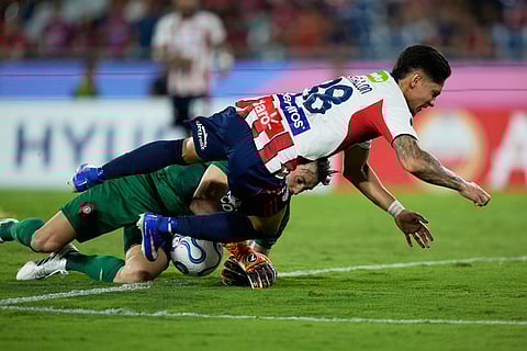 Brayan Castrillon of Colombia's Junior, front, fights for the ball with goalkeeper Alexis Martin of Paraguay's Cerro Porteño during a Copa Libertadores Group F soccer match in Asuncion, Paraguay.