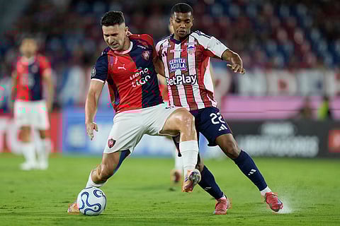 Jorge Morel of Paraguay's Cerro Porteño, left, and Jesus Rivas of Colombia's Junior fight for the ball during a Copa Libertadores Group F soccer match in Asuncion, Paraguay.