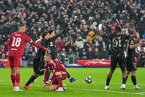 Liverpool's Alexis Mac Allister, center, goes down for a penalty which was later overturned after a VAR review during the Champions League quarterfinal second leg soccer match between Liverpool and Paris Saint-Germain in Liverpool, England.