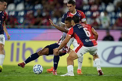 Jesus Rivas of Colombia's Junior, center, fights for the ball with Victor Velazquez, top, and Brian Luciatti of Paraguay's Cerro Porteño during a Copa Libertadores Group F soccer match in Asuncion, Paraguay.