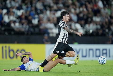 Santiago Del Valle of Paraguay's Libertad, top, is brought down by Emanuel Coronel of Argentina's Rosario Central during a Copa Libertadores Group H soccer match in Asuncion, Paraguay.
