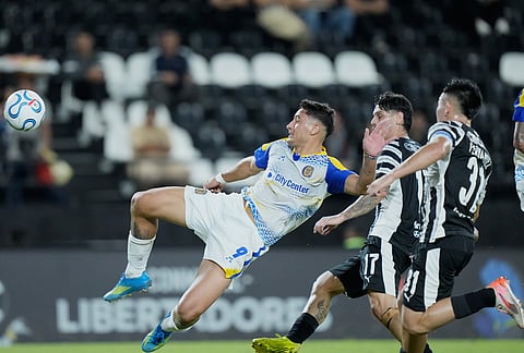 Alejo Veliz of Argentina's Rosario Central, left, attempts to shoot the ball during a Copa Libertadores Group H soccer match against Paraguay's Libertad in Asuncion, Paraguay.