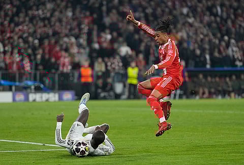 Real Madrid's Ferland Mendy, left, challenges for the ball with Bayern's Michael Olise during the Champions League quarterfinal second leg soccer match between Bayern Munich and Real Madrid in Munich, Germany.