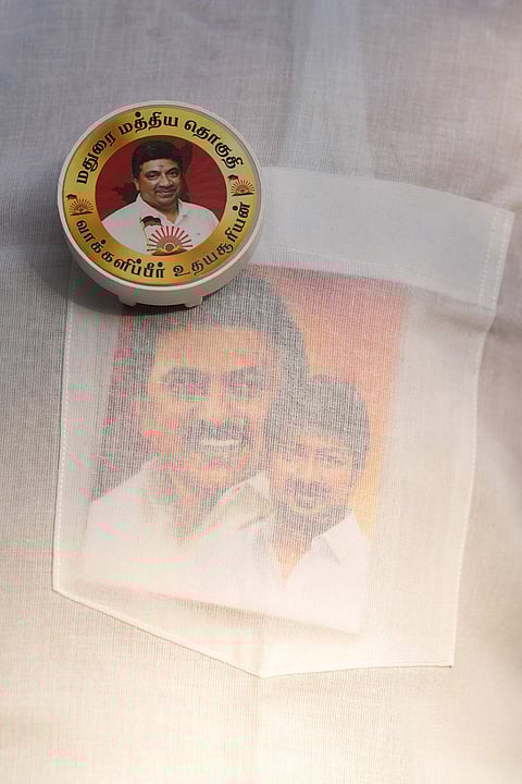 A supporter wearing a badge of Palanivel Thiaga Rajan and carrying a photo of M. K. Stalin in his pocket during the Tamil Nadu Assembly Election 2026.