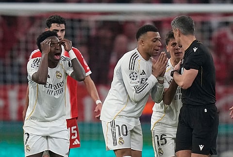 Real Madrid's Kylian Mbappe, center, and Vinicius Jr., left, disagree with referee Slavko Vincic during the Champions League quarterfinal second leg soccer match between Bayern Munich and Real Madrid in Munich, Germany.