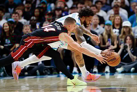 Charlotte Hornets forward Miles Bridges, back, and Miami Heat guard Tyler Herro (14) battle for a loose ball during the first half of an NBA play-in tournament basketball game in Charlotte, North Carolina.