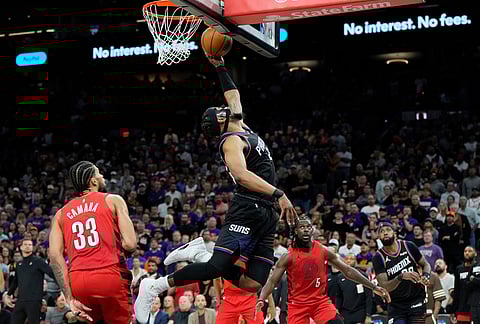 Phoenix Suns guard Jordan Goodwin, center, scores as Portland Trail Blazers forward Toumani Camara (33), Trail Blazers guard Jrue Holiday (5) and Suns forward Royce O'Neale, right, look on during the second half of an NBA play-in tournament basketball game, in Phoenix.