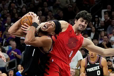 Phoenix Suns guard Devin Booker (1) gets fouled by Portland Trail Blazers forward Deni Avdija (8) during the second half of an NBA play-in tournament basketball game, in Phoenix. 