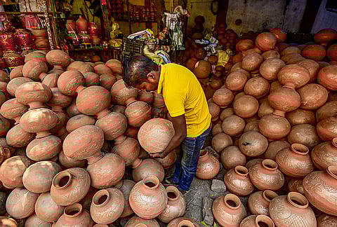 A shopkeeper stacks claypots at a shop on a hot summer day, in Prayagraj, Uttar Pradesh.