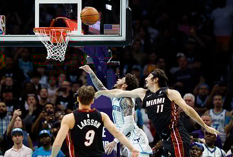 Charlotte Hornets guard LaMelo Ball, center, scores the game-winning basket as Miami Heat forward Jaime Jaquez Jr. (11) and guard Pelle Larsson (9) look on during the second half of an NBA play-in tournament basketball game in Charlotte, North Carolina.