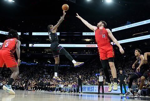 Phoenix Suns guard Jalen Green (4) shoots over Portland Trail Blazers center Donovan Clingan (23) as Trail Blazers guard Jrue Holiday (5) and Suns forward Oso Ighodaro, right, look on during the second half of an NBA play-in tournament basketball game in Phoenix.