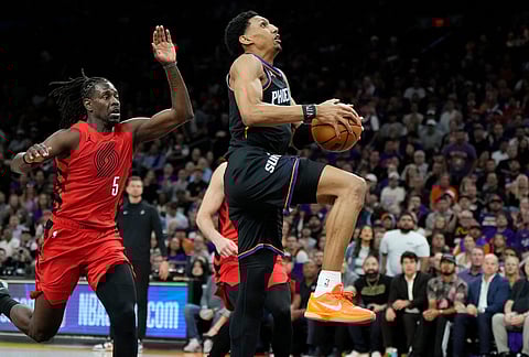 Phoenix Suns forward Ryan Dunn, right, drives past Portland Trail Blazers guard Jrue Holiday (5) during the second half of an NBA play-in tournament basketball game, in Phoenix.