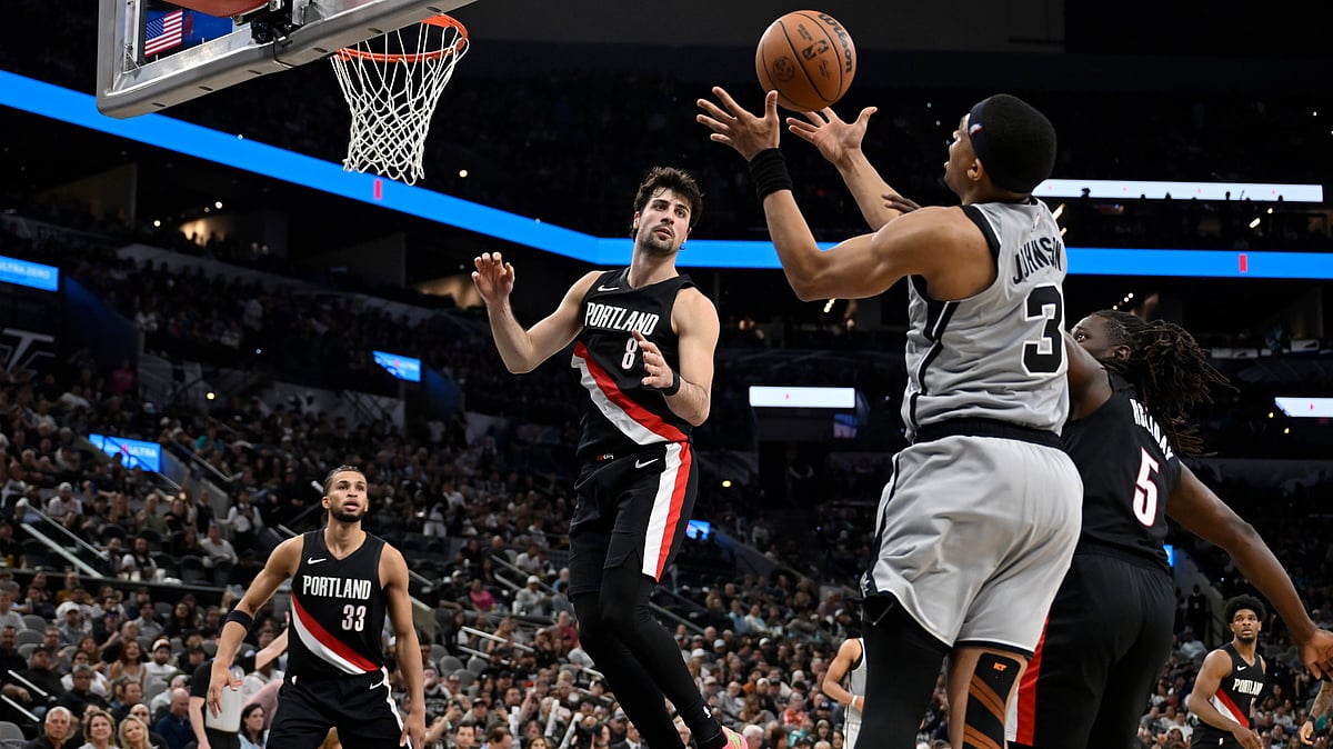San Antonio Spurs forward Keldon Johnson (3) grabs the rebound ahead of Portland Trail Blazers' Jrue Holiday (5) and Deni Avdija (8) during the second half of an NBA basketball game. - AP Photo