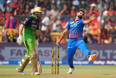 Delhi Capitals' Auqib Nabi bowls a delivery as Royal Challengers Bengaluru's Phil Salt watches during the Indian Premier League cricket match between Royal Challengers Bengaluru and Delhi Capitals in Bengaluru.