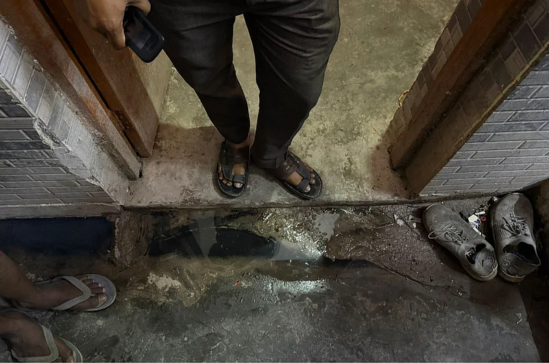 Rakesh, one of the factory workers, stands on the edge of his room, holding a button phone