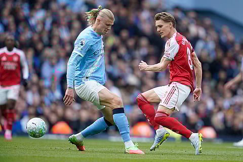 Manchester City's Erling Haaland challenges for the ball with Arsenal's Martin Odegaard during the English Premier League soccer match between Manchester City and and Arsenal, in Manchester, England.