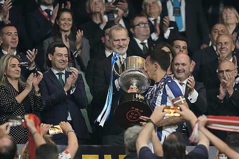 Spain's King Felipe VI, centre, looks as Real Sociedad's Mikel Oyarzabal kisses the trophy after the Copa del Rey final soccer match between Atletico Madrid and Real Sociedad in Seville, Spain.
