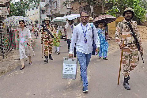 Poll officials carry election materials as they move to conduct home voting for senior citizens at Sonarpur North Assembly constituency, in Kolkata.
