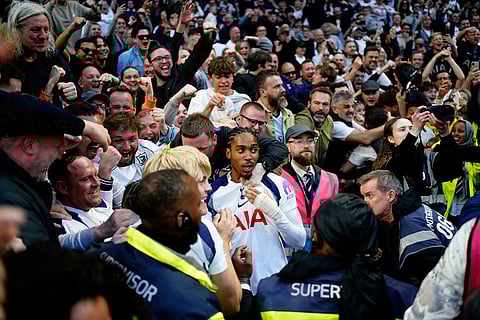 Tottenham Hotspur's Djed Spence is mobbed by fans in the crowd after team-mate Xavi Simons (hidden) scores their side's second goal of the game during their English Premier League soccer match against Brighton & Hove Albion in London.